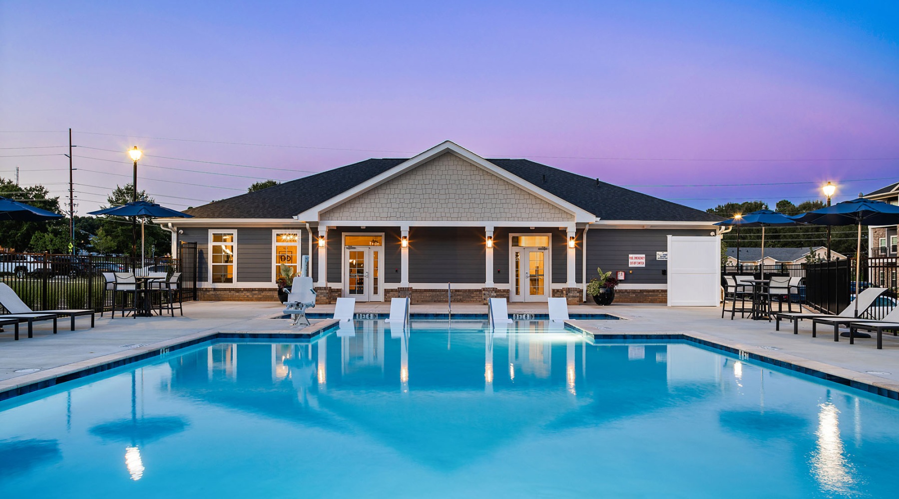 resort style pool with seating with a building behind it