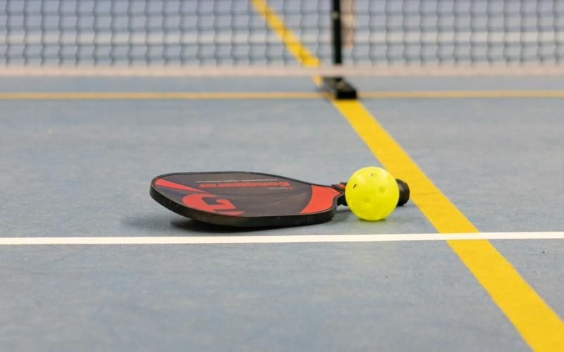 a pickle ball racket and a yellow ball